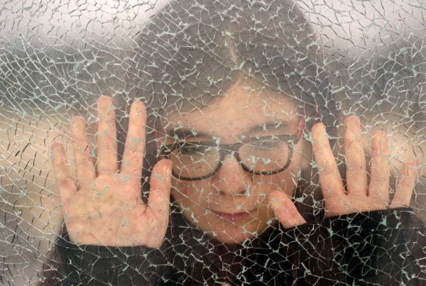 A person leaning up against a frosted glass window.