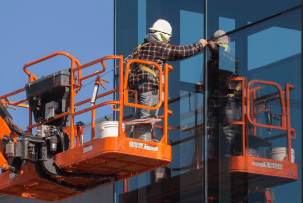 window film installer on a crane checking the windows on a commercial building