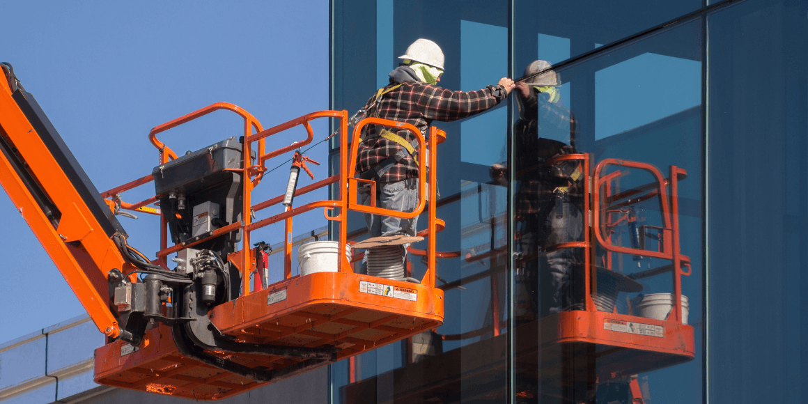 window film installer on a crane checking the windows on a commercial building